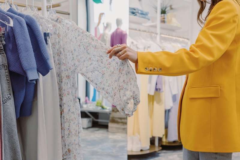Shopper browsing clothes in a retail store with background music
